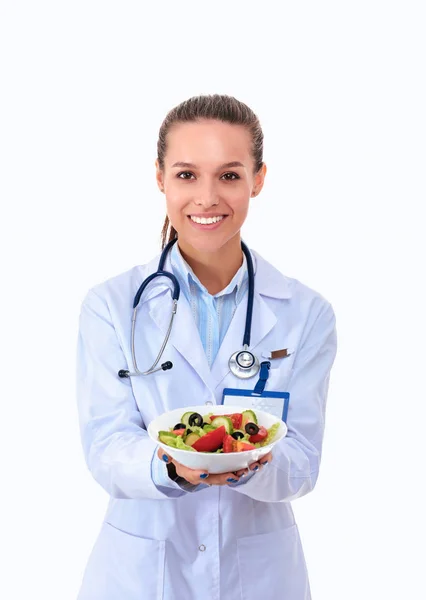 Portrait of a beautiful woman doctor holding a plate with fresh vegetables. — Stock Photo, Image