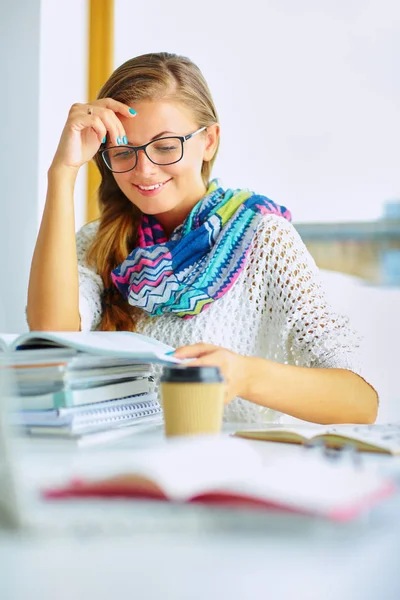 Kitapların arasında masa başında oturan genç bir kadın.