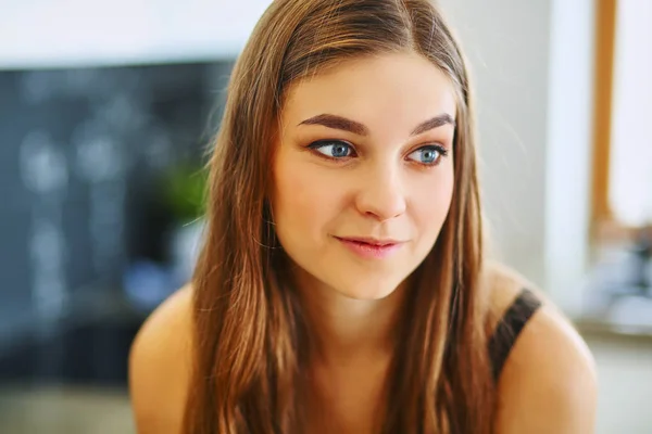 Jonge vrouw zitten in de buurt van tafel in de keuken — Stockfoto