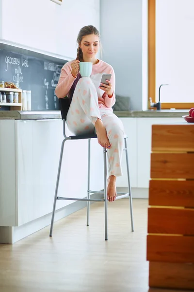 使用移动电话坐在现代厨房的女人 — 图库照片
