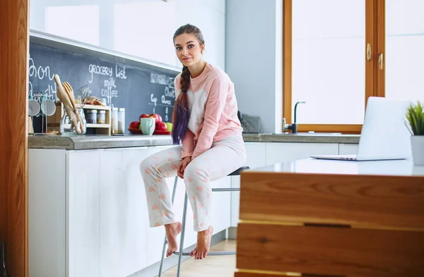 Ung kvinna sitter nära bord i köket — Stockfoto