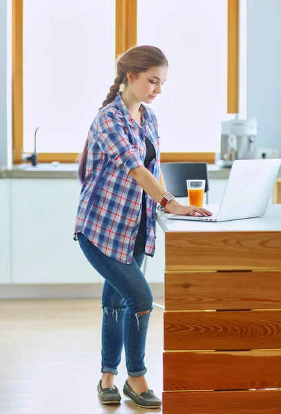 Junge Frau steht mit Laptop in Küche — Stockfoto