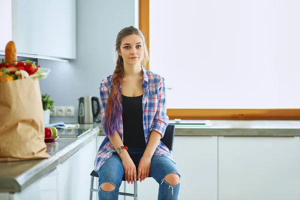 Mladá žena sedí u stolu v kuchyni — Stock fotografie