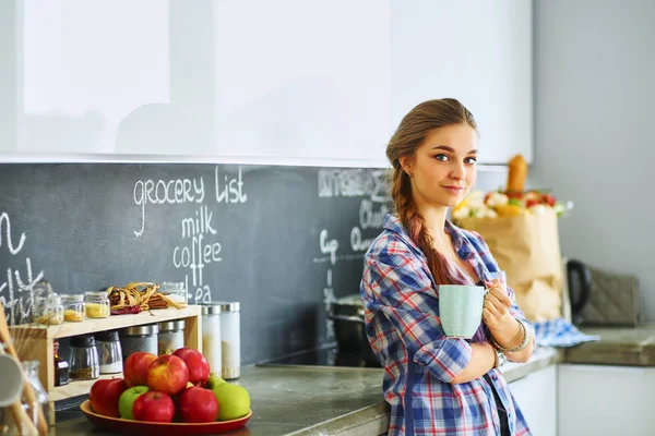 Happy woman drinking tea in the kitchen at home — Stock Photo, Image