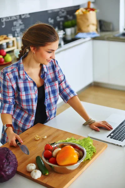 Молодая женщина режет овощи на кухне возле стола — стоковое фото