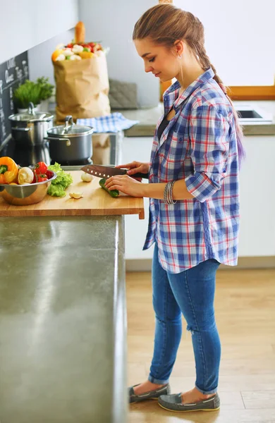 Jonge vrouw snijden van groenten in de keuken in de buurt van bureau — Stockfoto