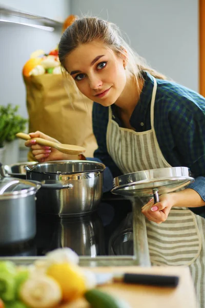 Jonge vrouw koken in haar keuken staan in de buurt kachel — Stockfoto