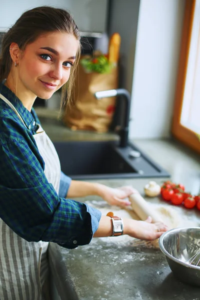 Vacker kvinna matlagning tårta i köket står nära skrivbordet — Stockfoto