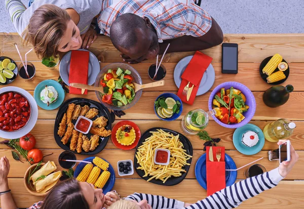 Top view group of people having dinner together while sitting at wooden table