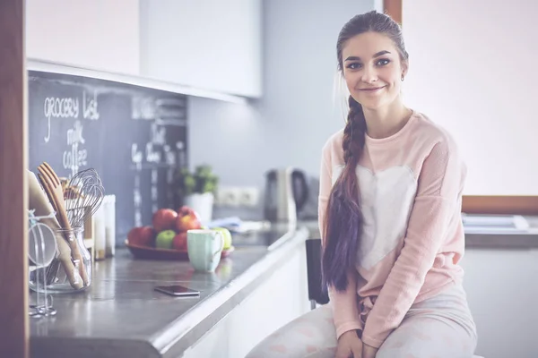 Ung kvinna sitter nära bord i köket — Stockfoto
