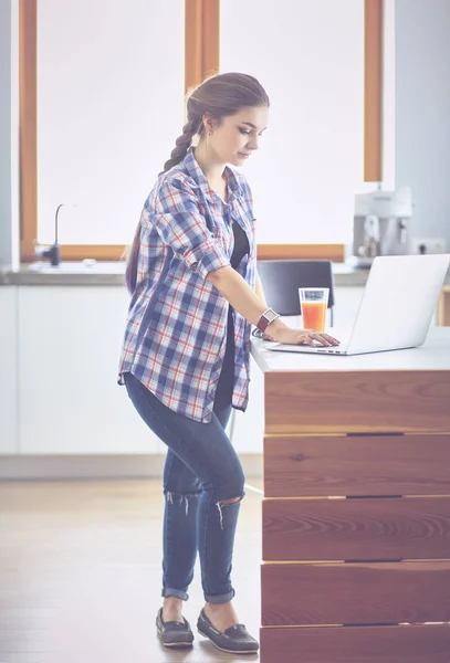ラップトップを使用して台所に立っている若い女性 — ストック写真