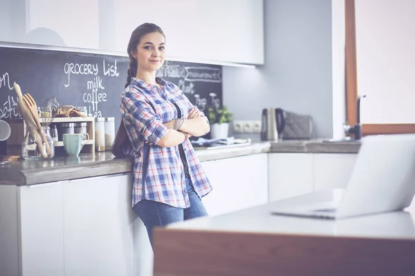 Ritratto di giovane donna con le braccia incrociate sullo sfondo della cucina — Foto Stock