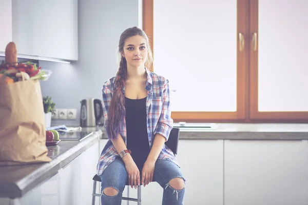 Fiatal nő ül közelében táblázat a konyhában — Stock Fotó