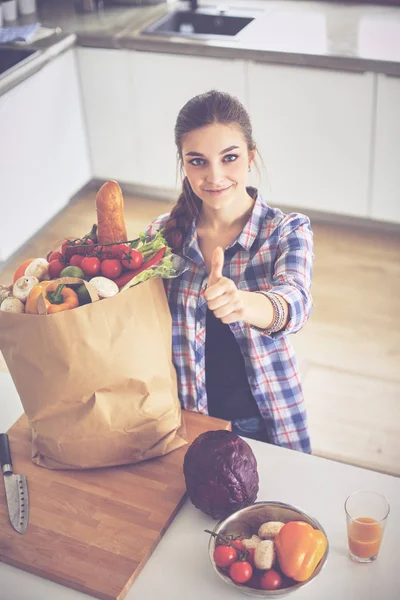 Молодая женщина держит продуктовый пакет с овощами и показывает в порядке — стоковое фото