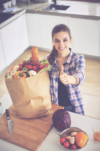 Fiatal nő gazdaság élelmiszerbolt bevásárló táska zöldségekkel, és mutatja, oké — Stock Fotó