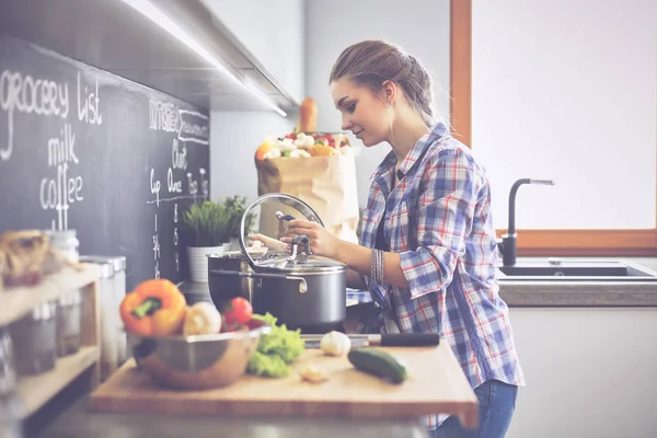 Mutfakta sobanın yanında duran genç bir kadın.