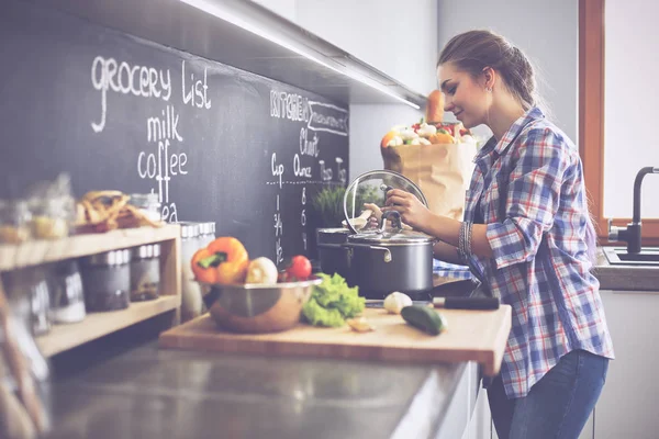 Mutfakta sobanın yanında duran genç bir kadın.