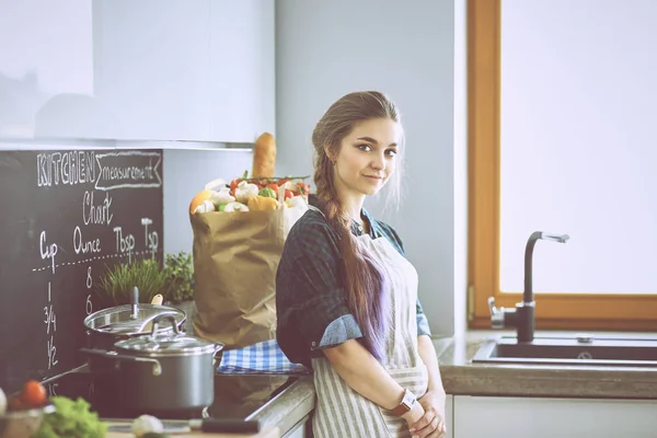 Junge Frau steht am Herd in der Küche — Stockfoto