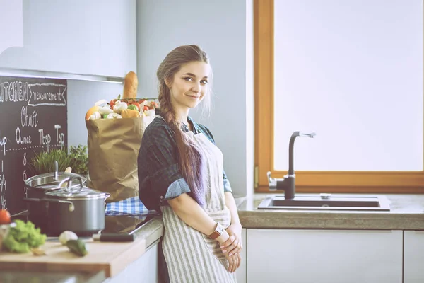 Mujer joven parada junto a la estufa en la cocina —  Fotos de Stock