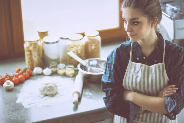 아름다운 여성이 부엌에서 책상 옆에 서서 케이크를 요리하고 있습니다 — 스톡 사진