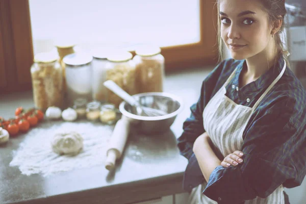 Vacker kvinna matlagning tårta i köket står nära skrivbordet — Stockfoto