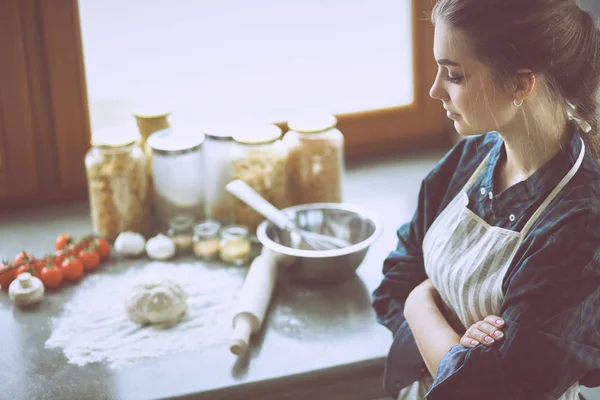 Όμορφη γυναίκα μαγείρεμα κέικ στην κουζίνα στέκεται κοντά στο γραφείο — Φωτογραφία Αρχείου