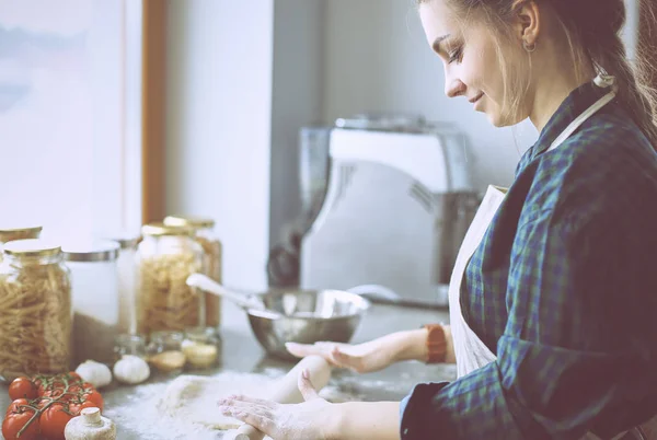 Hermosa mujer cocinando pastel en la cocina de pie cerca del escritorio — Foto de Stock