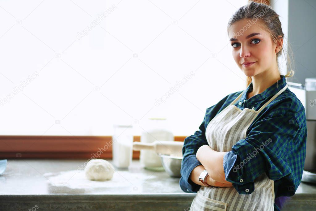 Beautiful woman cooking cake in kitchen standing near desk