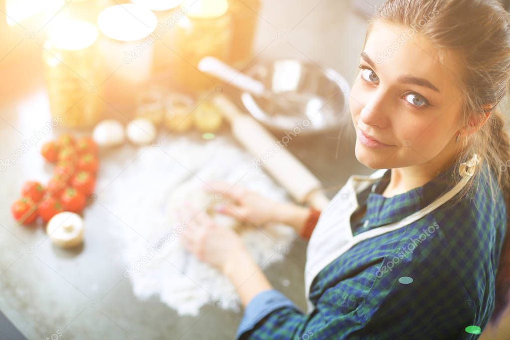 Beautiful woman cooking cake in kitchen standing near desk