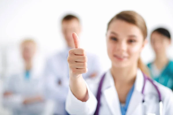 Médica atraente na frente do grupo médico mostrando ok — Fotografia de Stock