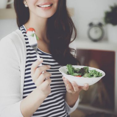 Salata yemek ve karışık salata tutan genç kadın