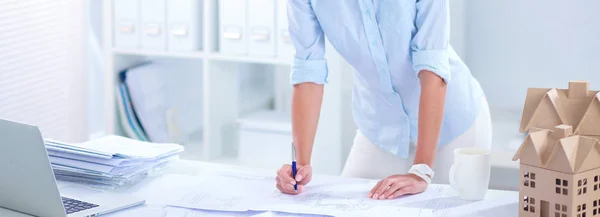 Portrait of female architect with blueprints at desk in office — Stock Photo, Image