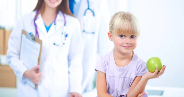 Концепция ребенка и медицины - женщина-врач дарит яблоко маленькой девочке — стоковое фото