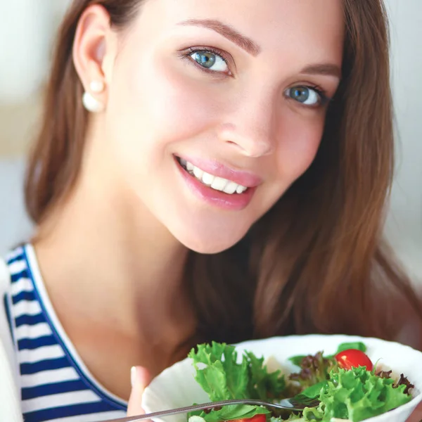 年轻女人吃沙拉和持有一份综合的沙拉 — 图库照片