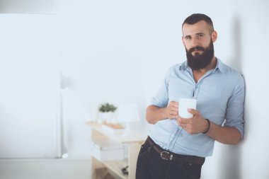 Duvara yakın duran ve kahve tutan genç adam