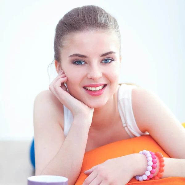 Smiling young woman lying on a white floor with pillow — Stock Photo, Image