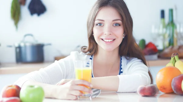 Mujer joven sentada cerca de escritorio en la cocina —  Fotos de Stock