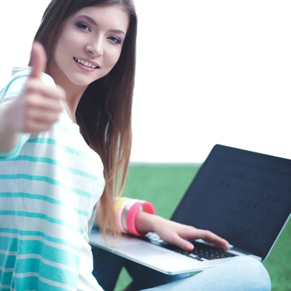 Young woman with laptop sitting on green grass — Stock Photo, Image