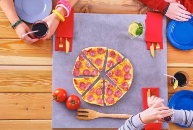 Bir grup genç insan pizza masada yemek.