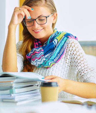 Kitapların arasında masa başında oturan genç bir kadın.