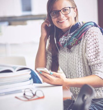 Kitapların arasında masa başında oturan genç bir kadın.