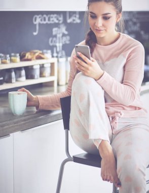 modern mutfakta otururken cep telefonu kullanan kadın