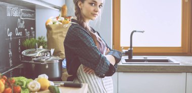 Mutfakta sobanın yanında duran genç bir kadın.