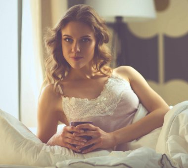 Genç kadın yatakta yatan ise kahve veya çay içme