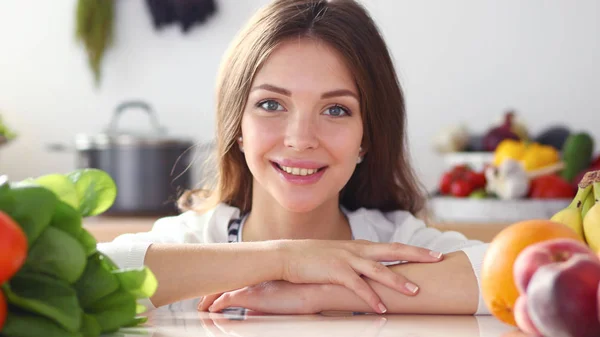 Mujer joven de pie cerca de escritorio en la cocina — Foto de Stock