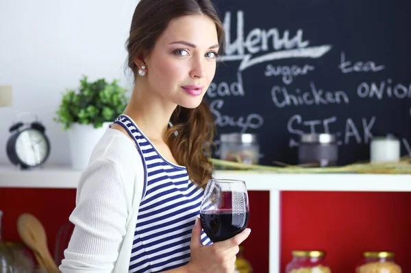 Mujer bonita bebiendo un poco de vino en casa en la cocina —  Fotos de Stock