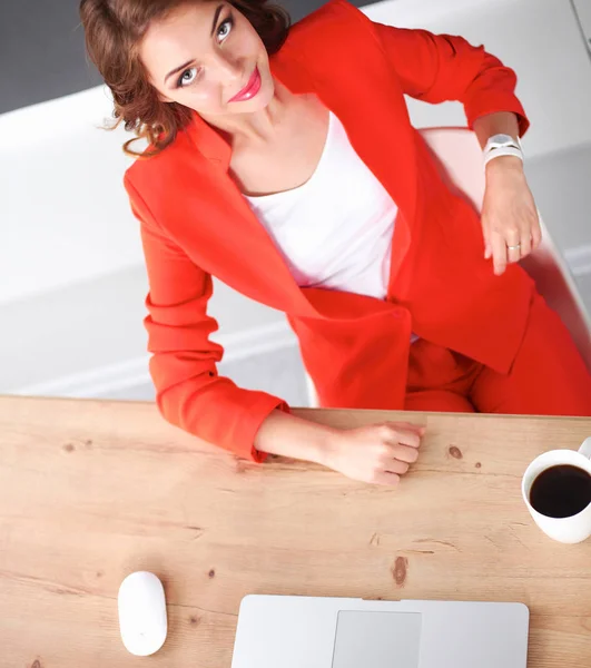 Mulher atraente sentada na mesa no escritório, trabalhando com computador portátil — Fotografia de Stock