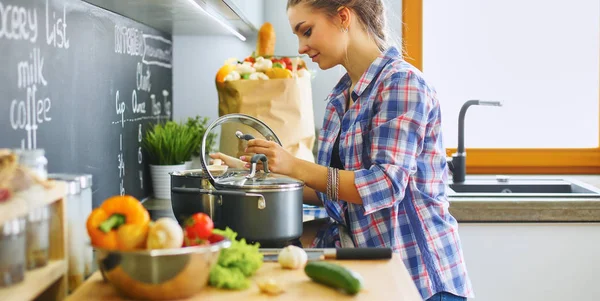 Jonge vrouw bij het fornuis in de keuken — Stockfoto