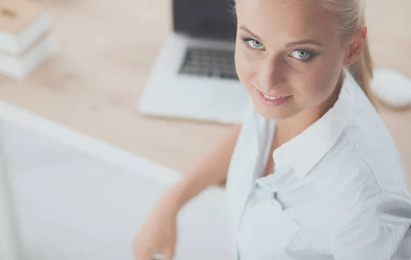 Aantrekkelijke zakenvrouw zit op een bureau met laptop in het kantoor — Stockfoto