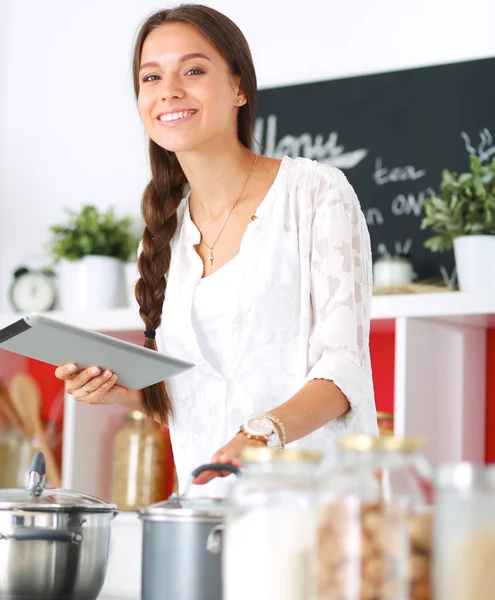 Mujer joven usando una tableta para cocinar en su cocina —  Fotos de Stock